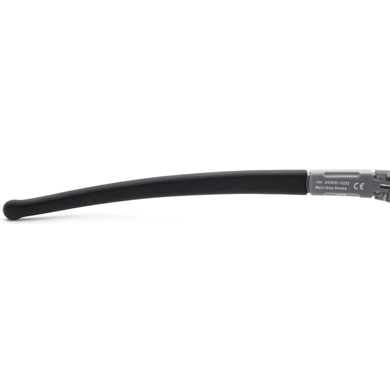 May include: Black rubber temple arm for eyeglasses with a grey plastic end piece that says "144 OXED91-0233 Satin Grey Smoke CE".