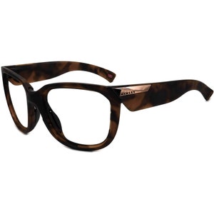 May include: Tortoise shell eyeglasses with a rose gold Oakley logo on the side.