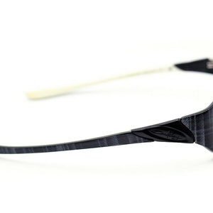 May include: Black and gray patterned eyeglasses with a white temple arm and the Oakley logo on the side.