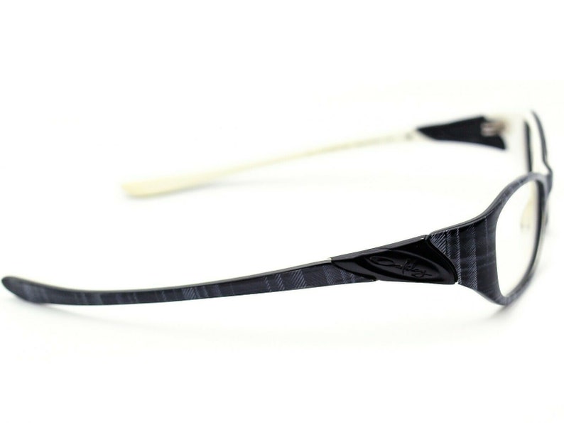 May include: Black and gray patterned eyeglasses with a white temple arm and the Oakley logo on the side.