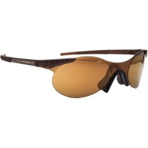 May include: Brown and gold Oakley sunglasses with a rimless design and brown lenses.
