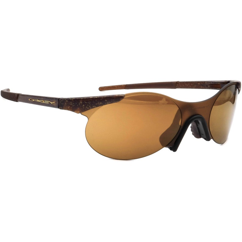 May include: Brown and gold Oakley sunglasses with a rimless design and brown lenses.
