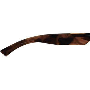May include: Close-up of the tortoiseshell brown frame of a pair of sunglasses. The frame has the text "OO9432-0650 59 16 125" printed on the inside.