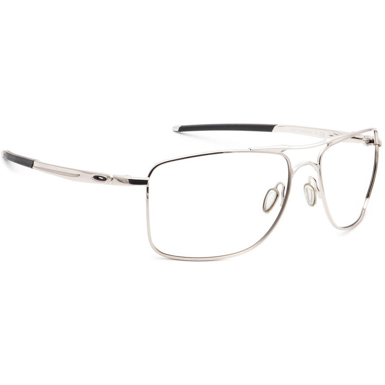 May include: Silver-toned metal frame eyeglasses with black accents on the arms. The glasses have a rectangular shape with a slightly rounded edge.