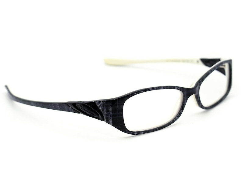 May include: Black and white patterned eyeglasses with a white frame. The glasses have a rectangular shape and clear lenses.