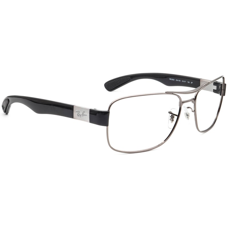 Puede incluir: Gafas rectangulares plateadas con patillas de pl&aacute;stico negro. Las patillas est&aacute;n etiquetadas con "Ray-Ban".