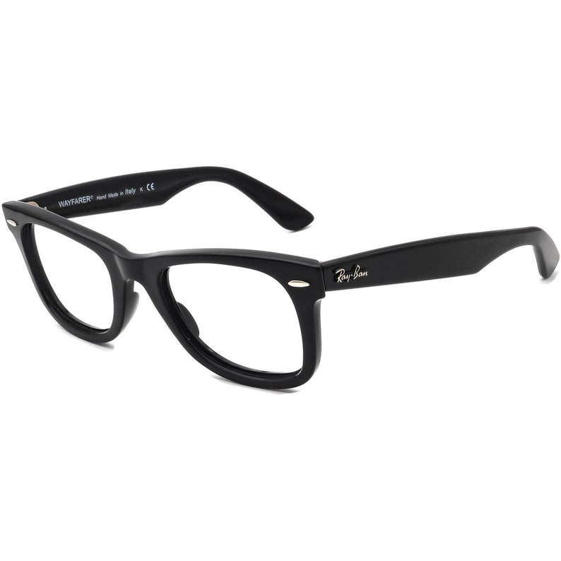 May include: Black plastic Wayfarer style spectacles with clear lenses. The glasses have a gold Ray-Ban logo on the right temple.