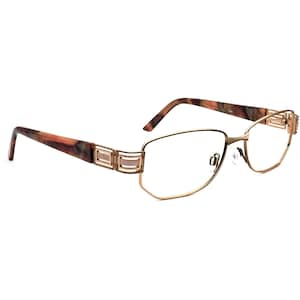 May include: Gold-tone metal eyeglasses with a tortoiseshell brown frame. The frame has a decorative design with gold accents.