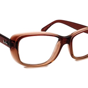 Puede incluir: Gafas de plástico de color marrón con lentes transparentes. El nombre de la marca "Ray-Ban" es visible en la patilla izquierda.