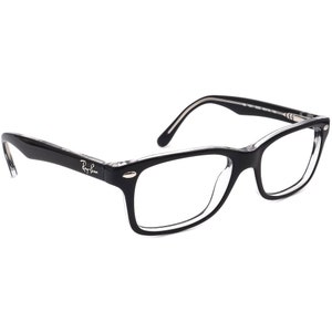 Puede incluir: Gafas de pasta negra con lentes transparentes. El nombre de la marca "Ray-Ban" está impreso en la patilla izquierda.