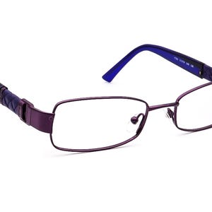 May include: Purple metal frame eyeglasses with blue temple arms. The frame has a rectangular shape with a thin metal design.