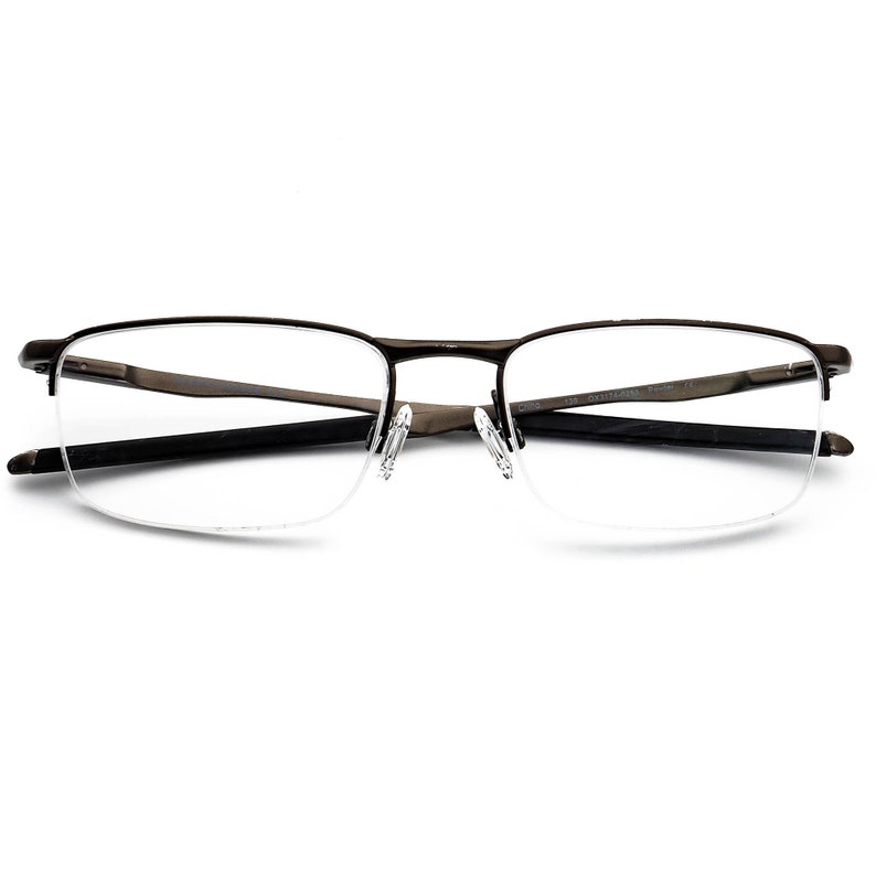 May include: A pair of black metal eyeglasses with a half-rim design and clear lenses. The glasses have a subtle curve to the frame.