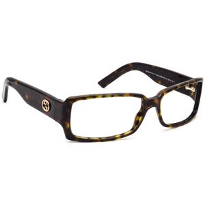 May include: Rectangular eyeglasses with a tortoiseshell pattern. The frames feature a gold-colored logo on the temples. The glasses have a classic, sophisticated design.
