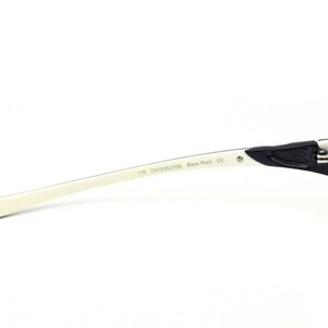 May include: White and black eyeglasses with a black plastic frame and white arms. The arms are labeled "134  DX1034-0152 Black Plaid CE".