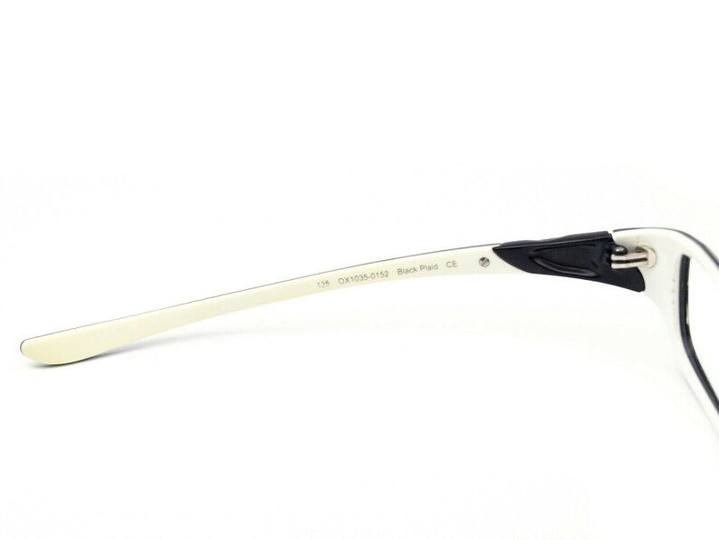 May include: White and black eyeglasses with a black plastic frame and white arms. The arms are labeled "134  DX1034-0152 Black Plaid CE".