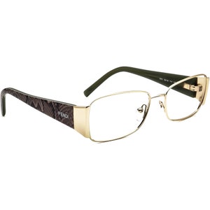 Può includere: Occhiali da vista con montatura dorata e un motivo marrone e nero. La montatura ha la scritta "FENDI" stampata.
