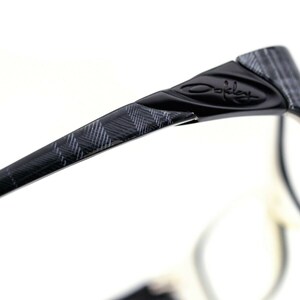 May include: Black and gray patterned eyeglasses with the Oakley logo on the side.