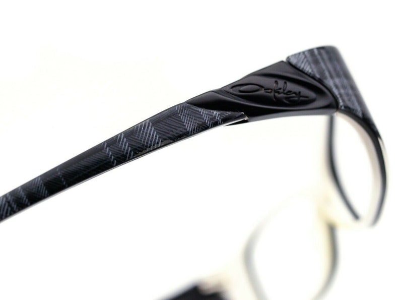 May include: Black and gray patterned eyeglasses with the Oakley logo on the side.