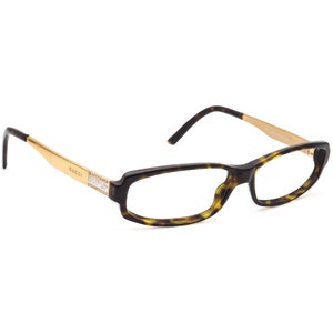 May include: Tortoise shell eyeglasses with gold accents and clear lenses. The frames have a rectangular shape and the brand name "GUCCI" is visible on the side.