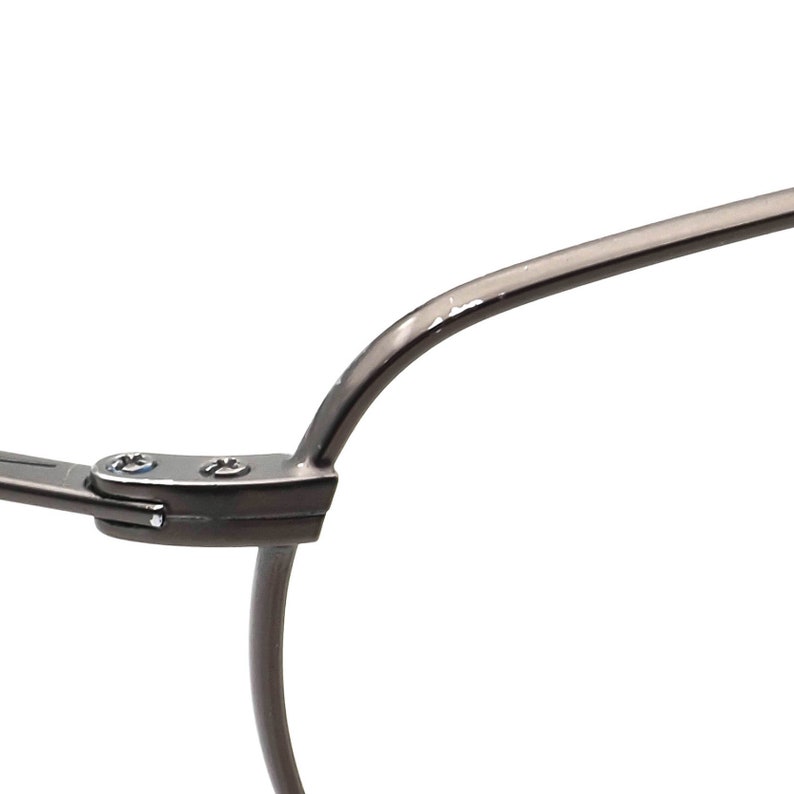 May include: Close-up of a section of eyeglasses. The frame is a dark gray metal with a curved design. The hinge is visible, with small screws securing the frame components. The background is plain white.