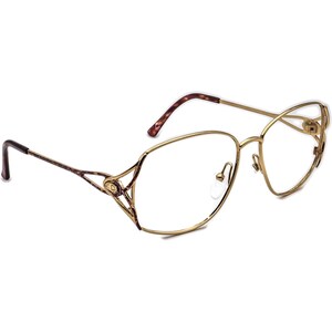 May include: Gold-tone metal eyeglasses with a delicate, intricate design on the frame. The lenses are clear.