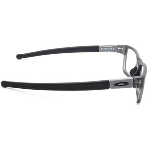 May include: Grey and black eyeglasses with a black rubber temple. The frame has a subtle curve and the text "Oakley" is visible on the side.