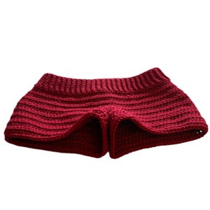 May include: Burgundy crochet shorts with a ribbed waistband and a flared, ruffled design. The crochet work has a textured appearance. The shorts are made of a soft, flexible material, suitable for warm weather.