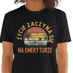 May include: Black t-shirt with a retro sunset graphic and the text "Życie zaczyna się na emeryturze" in Polish.