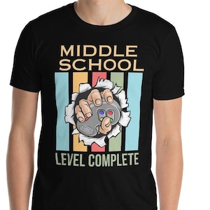 May include: Black t-shirt with a retro-style graphic of a hand holding a video game controller. The text "Middle School Level Complete" is printed on the shirt.