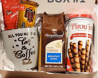 May include: Box #1 containing a mug with "All You Need Is Love & Coffee" text, chocolate bars, a bag of ground coffee, and a tin of chocolate hazelnut Pirouline wafers. The coffee bag is 4 oz (113g).