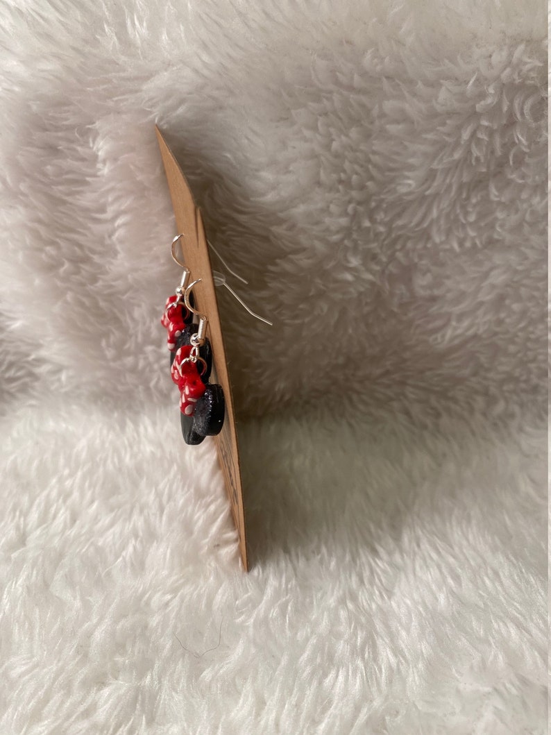 May include: A pair of dangle earrings with black and red beads. The earrings are on a brown card.