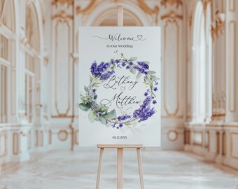 Puede incluir: Un cartel de bienvenida de boda blanco con una corona de lavanda y el texto "Bienvenido a nuestra boda" y "Bethany & Matthew" con la fecha "04.12.20XX".