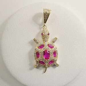 May include: Gold-tone turtle pendant with pink and white cubic zirconia stones.