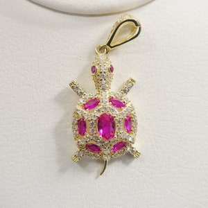 May include: Gold-tone turtle pendant with pink and white cubic zirconia stones.