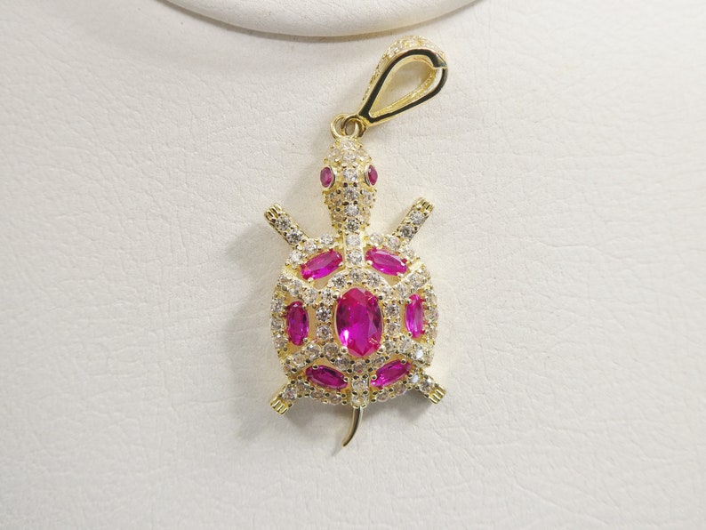 May include: Gold-tone turtle pendant with pink and white cubic zirconia stones.