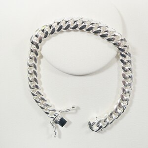 May include: A silver curb chain bracelet with a lobster clasp closure.