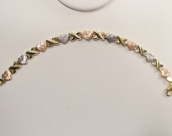 Pulsera tricolor de oro amarillo macizo de 10k con el diseño de corazones, abrazos y besos.