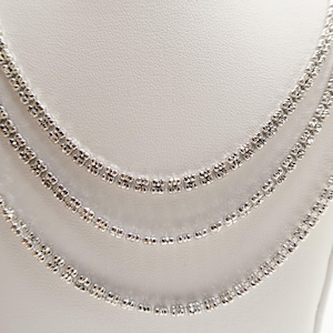 May include: A close-up of three silver necklaces displayed on a white mannequin. The necklaces have different designs, with one featuring small, round beads and the others showcasing a floral-like pattern. The jewelry is set against a plain white background.