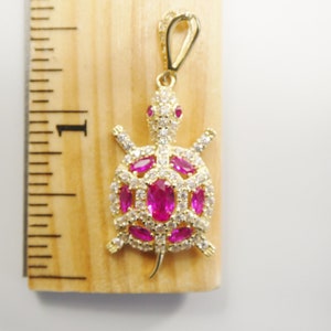 May include: Gold-tone turtle pendant with pink and white cubic zirconia stones.