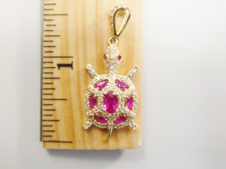 May include: Gold-tone turtle pendant with pink and white cubic zirconia stones.