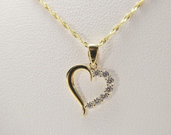 May include: A gold heart-shaped pendant necklace with clear cubic zirconia stones.