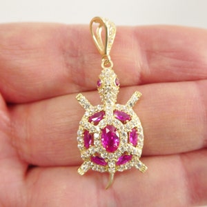 May include: Gold-tone turtle pendant with pink and white cubic zirconia stones.