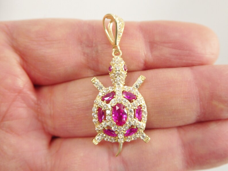 May include: Gold-tone turtle pendant with pink and white cubic zirconia stones.