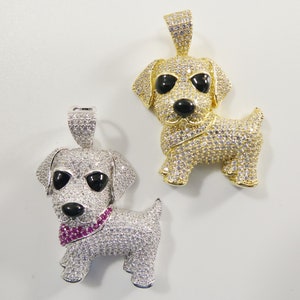 May include: Two silver and gold dog charm pendants with black eyes and white cubic zirconia stones. The silver pendant has a pink cubic zirconia stone collar.