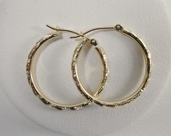 May include: A pair of gold hoop earrings with a textured design.
