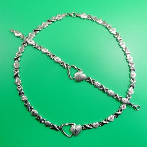 May include: Two silver necklaces with heart-shaped pendants. Each pendant has a small star design in the center.