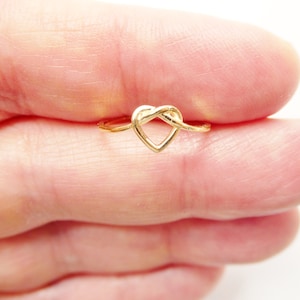 May include: A gold-colored ring with a heart-shaped knot design.