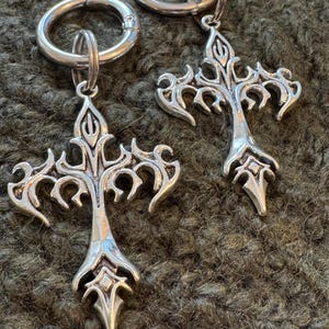 May include: Two silver keyrings with ornate cross-shaped charms. The charms have a detailed, intricate design with a pointed tip.