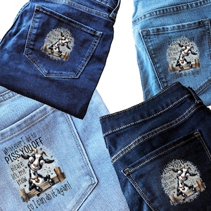 May include: Four pairs of denim jeans in various shades of blue. Each pair features a graphic on the back pocket with a cartoon goat and the text "Whatever I did to Piss You Off, Please Let Me Know So I Can Do It Again!"