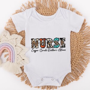 May include: White baby onesie with the word "NURSE" in colorful patterned letters. The text "Coffee. Scrubs. Rubbers. Gloves" is printed below the word "NURSE".
